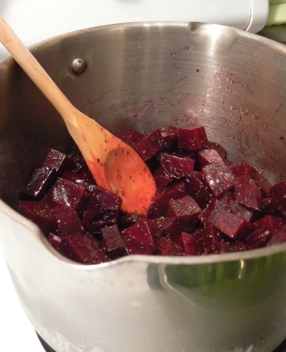 a wooden spoon in a silver pot filled with chopped beets