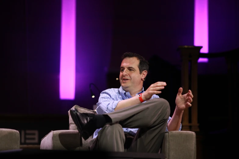 a man sitting on a chair and gesturing