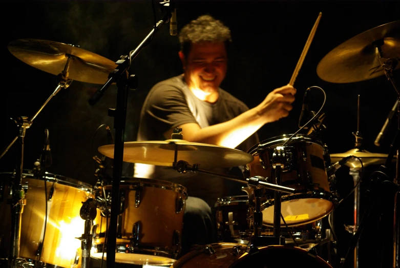 the drummer smiles as he plays the drums on stage