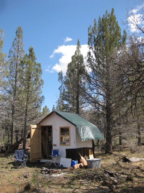 a small white shed sitting in the woods