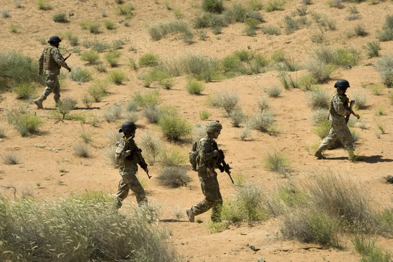 a group of soldiers are running through a desert