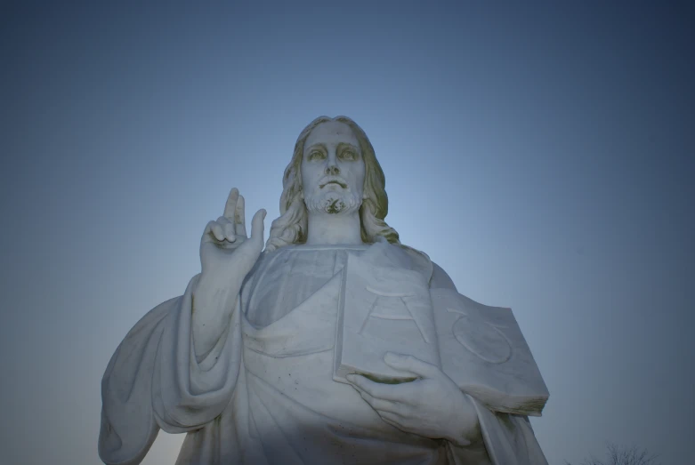 a statue is white with a man giving the sign