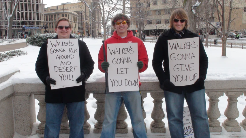 three young men in winter clothes are holding placares