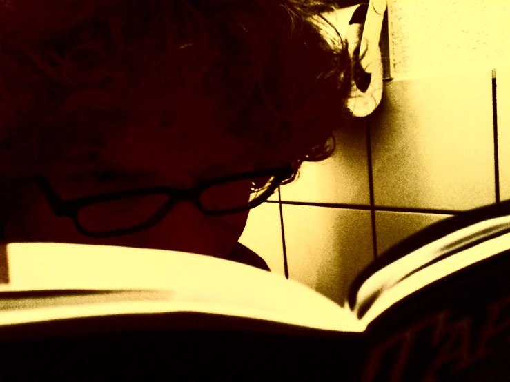 a person reading a book with glasses on