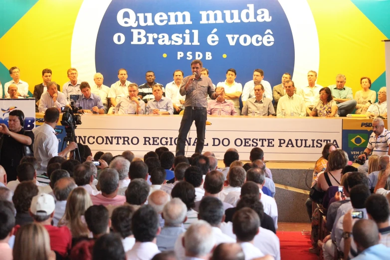 the audience is clapping and talking with the man standing on a stage