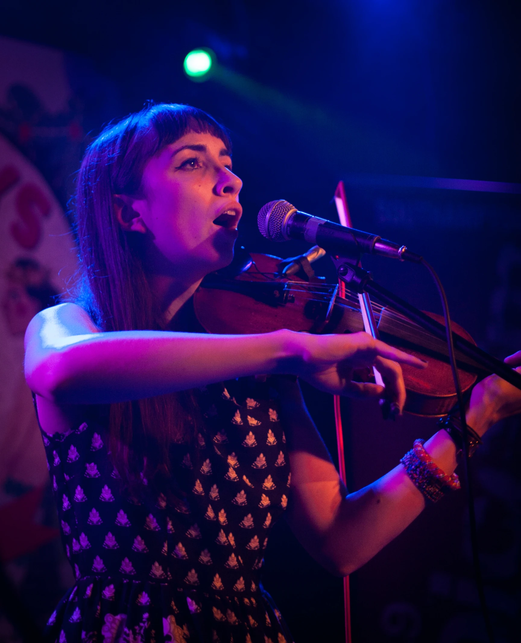 a woman standing at a microphone holding her violin