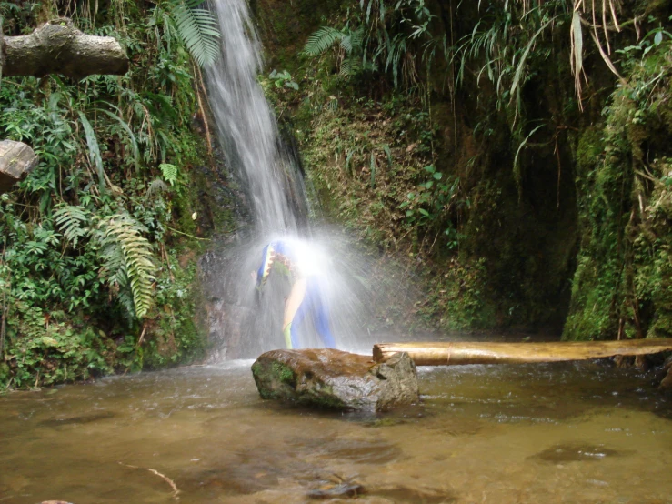 a man is on top of a rock near a waterfall