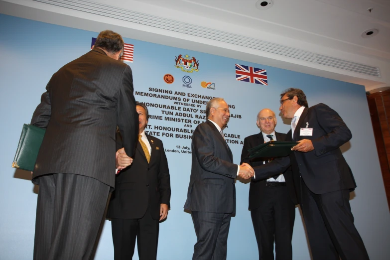 two men are shaking hands in front of three other men