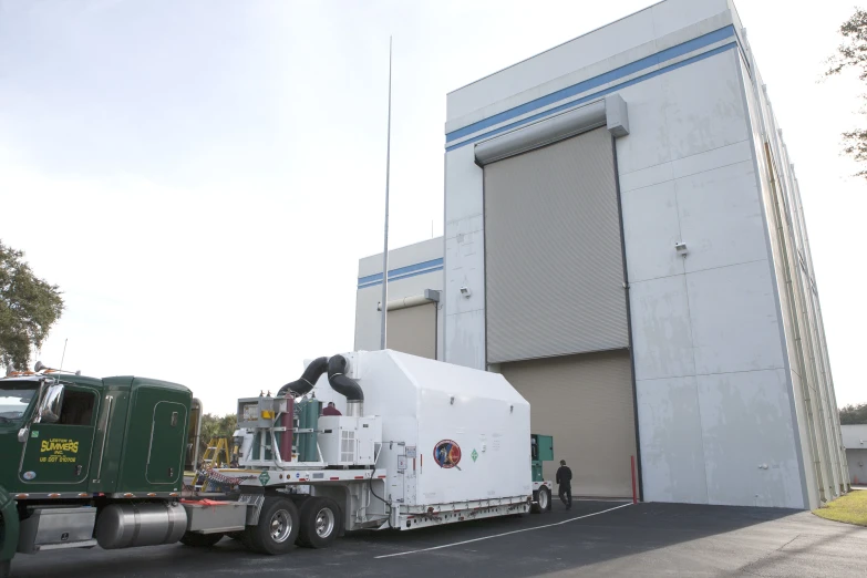 a green semi truck towing a white transport truck