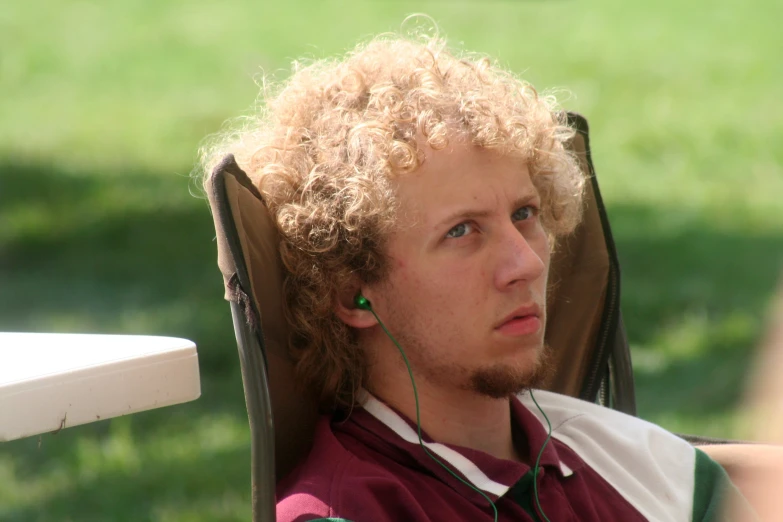 a man with curly hair sitting on a chair