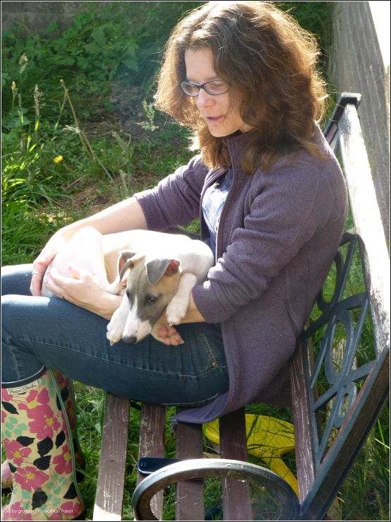 a woman holding a small white and grey dog on top of a bench