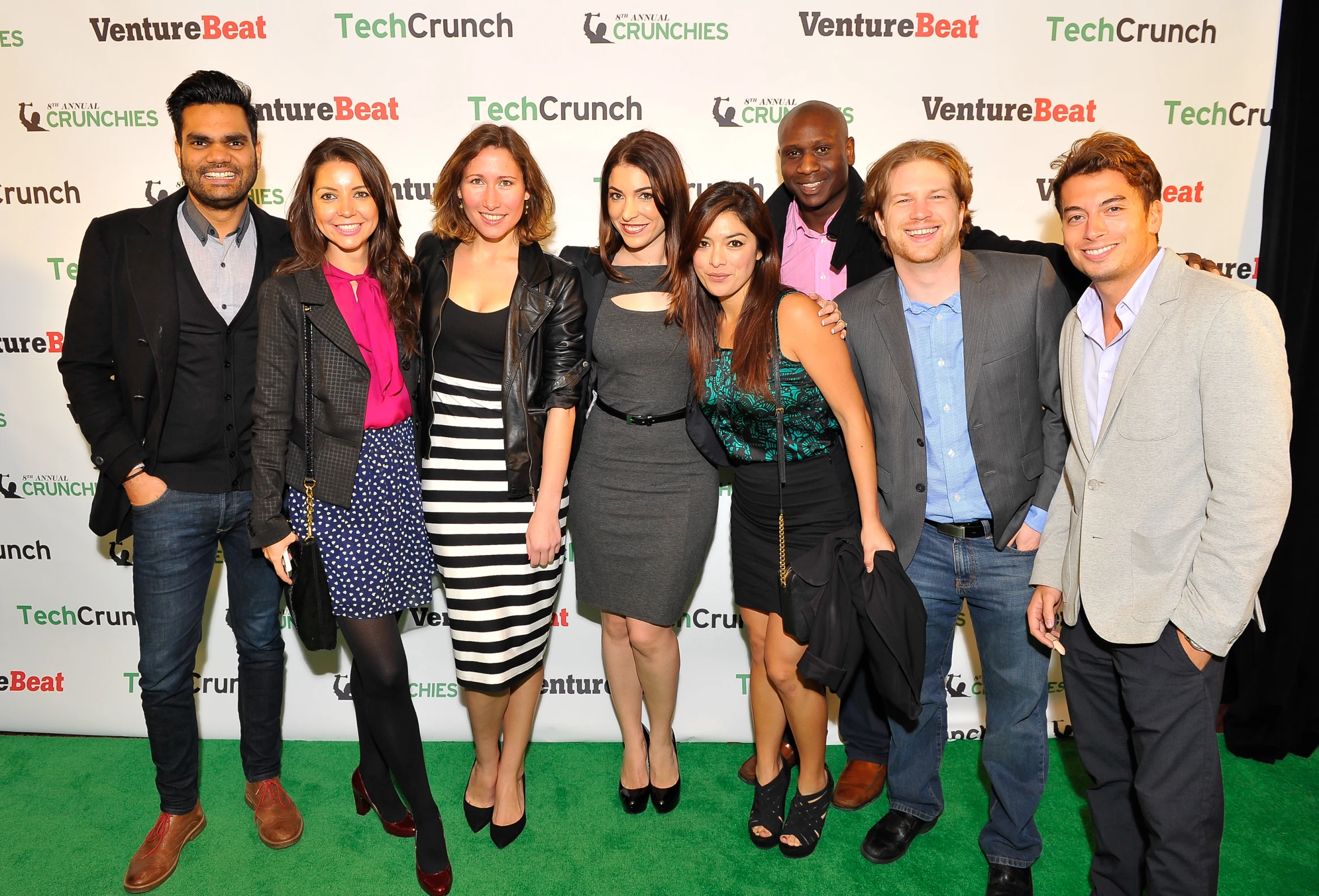 a group of people pose for the camera on a green carpet