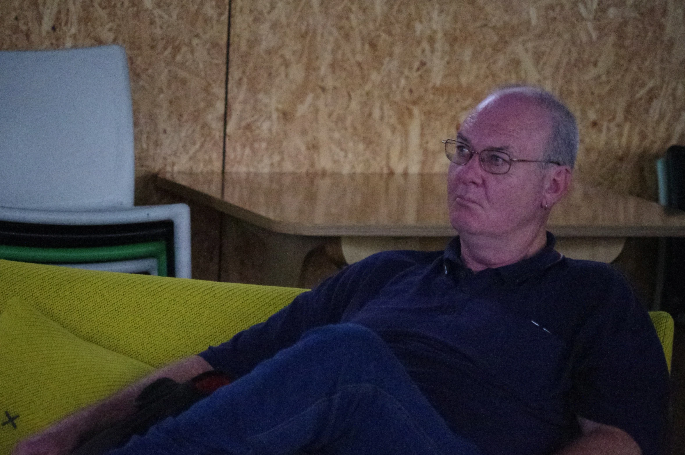 an older man sitting down in a chair with his feet on a pillow