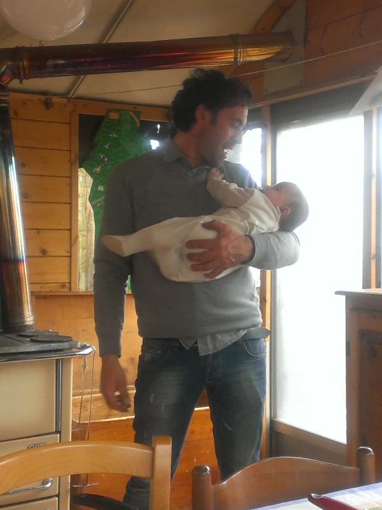 a man holds a baby inside a kitchen