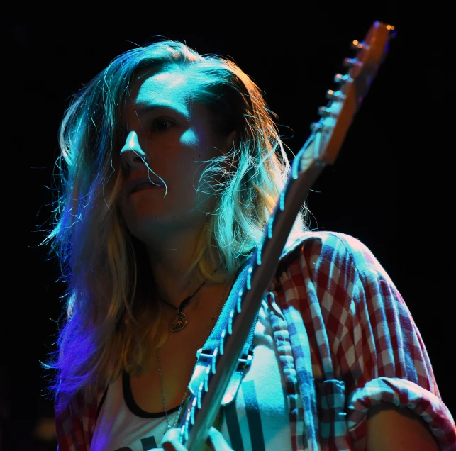 a woman playing guitar in front of a microphone