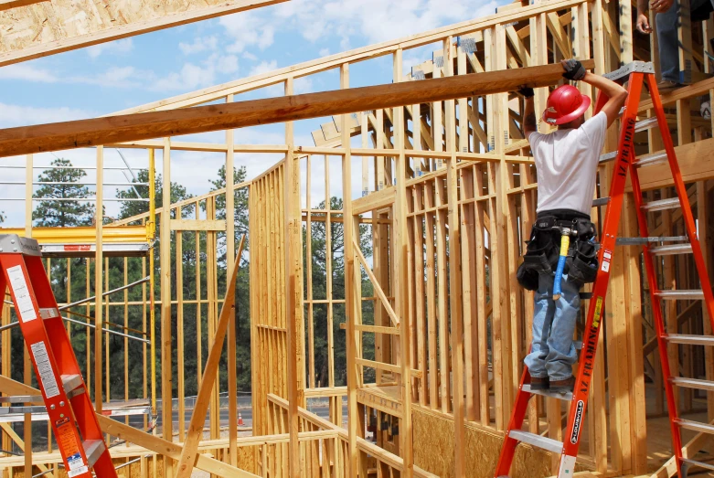 man wearing red hardhat on a ladder working inside