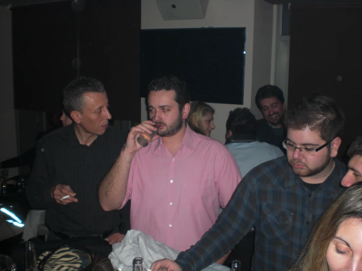 several people standing and sitting together in a room with drinks