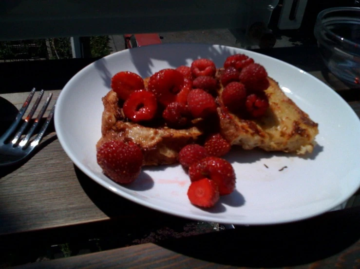 a plate with french toast and raspberries on it