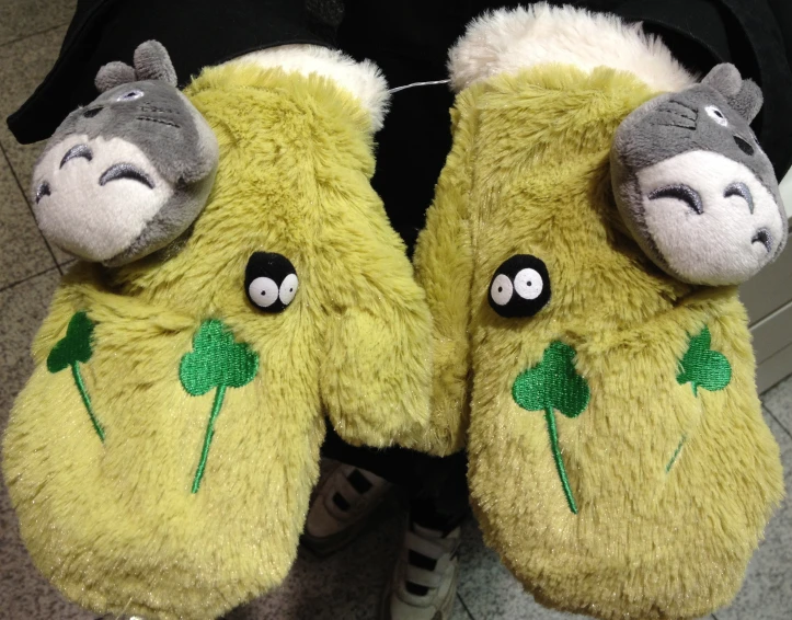 two stuffed animal slippers with a green clover and black eyes