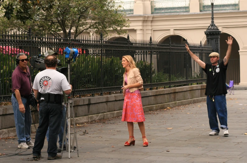 a woman in a pink dress standing on a street