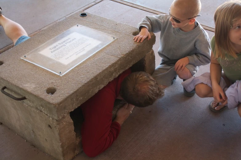 three children are sitting around playing with a brick box