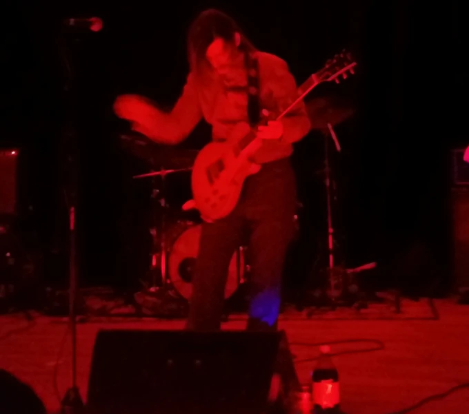 a man playing guitar in the dark on stage