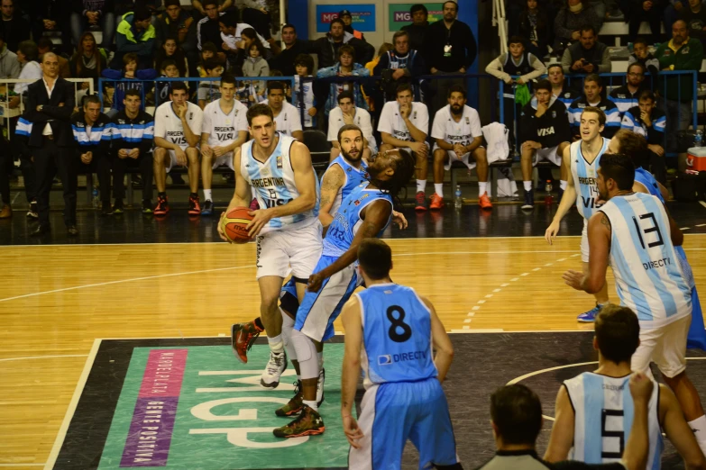 several players playing basketball on a court with people watching