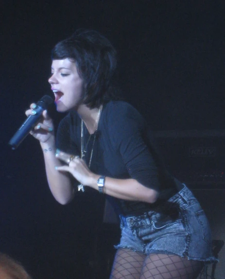 a female singer on stage performing with the microphone up to her mouth