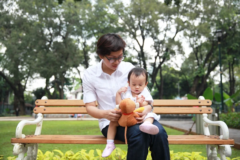 a woman and a baby sitting on a park bench