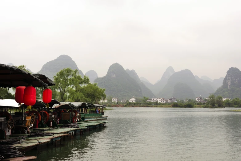 oriental decorations on stilts line a lake and mountain range