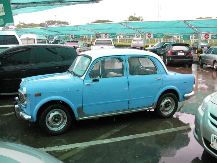 a blue car in front of cars that are parked in a lot