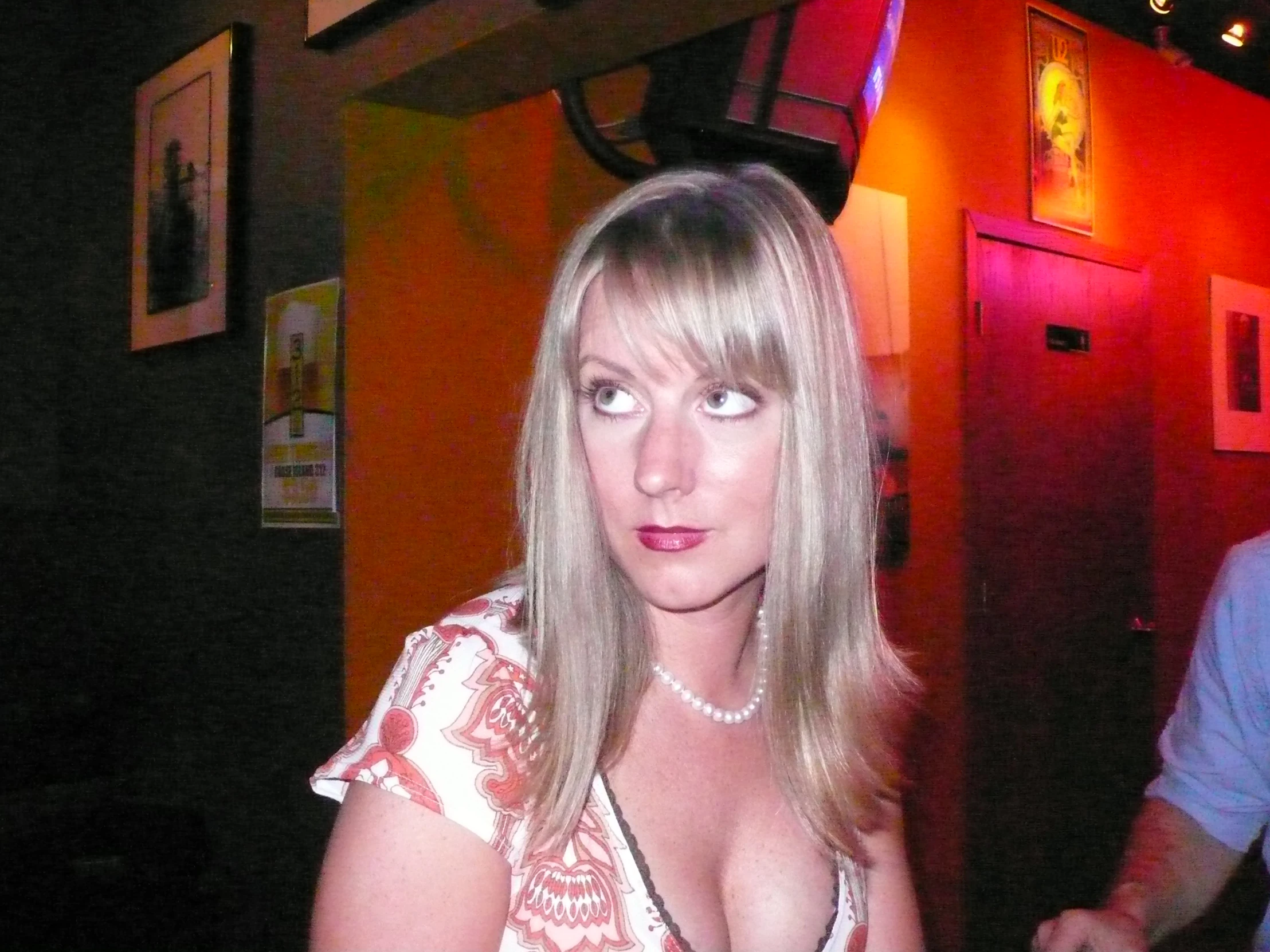 woman in pink dress standing at bar looking down