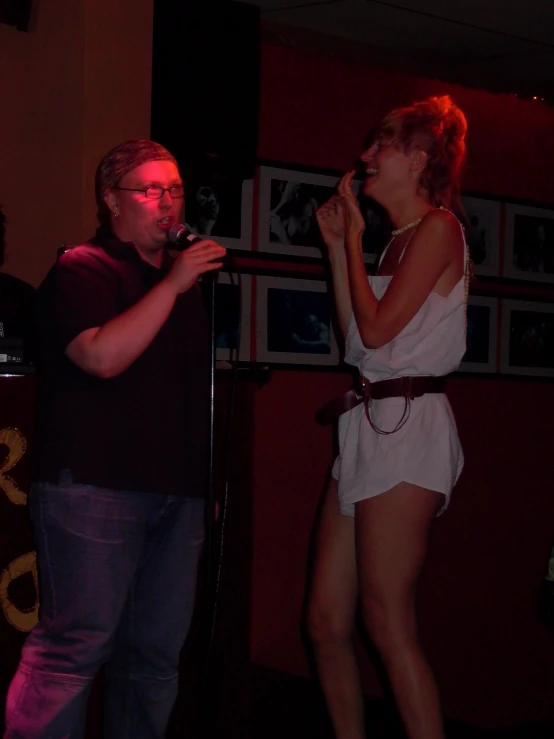 the two people are standing up singing into microphones
