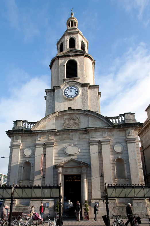 a tall church has clocks and bike racks in front