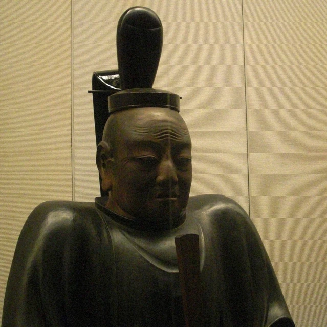 a statue of a seated man with a hat on top of his head