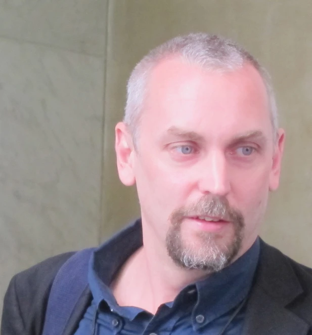 man with gray hair and beard in a black blazer