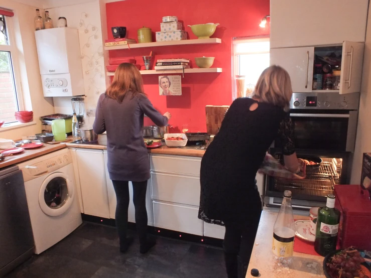 there are two woman standing at a kitchen counter preparing food