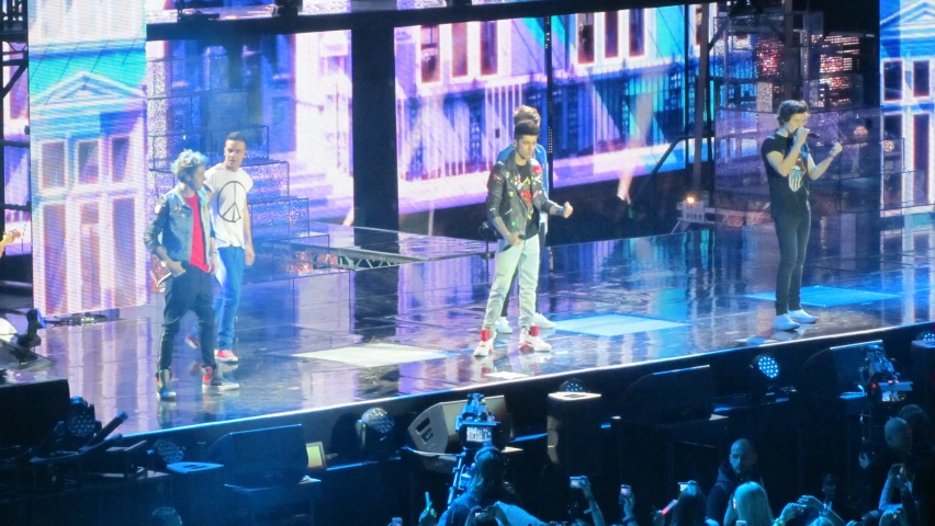 the people on the stage in front of a large crowd are watching the group