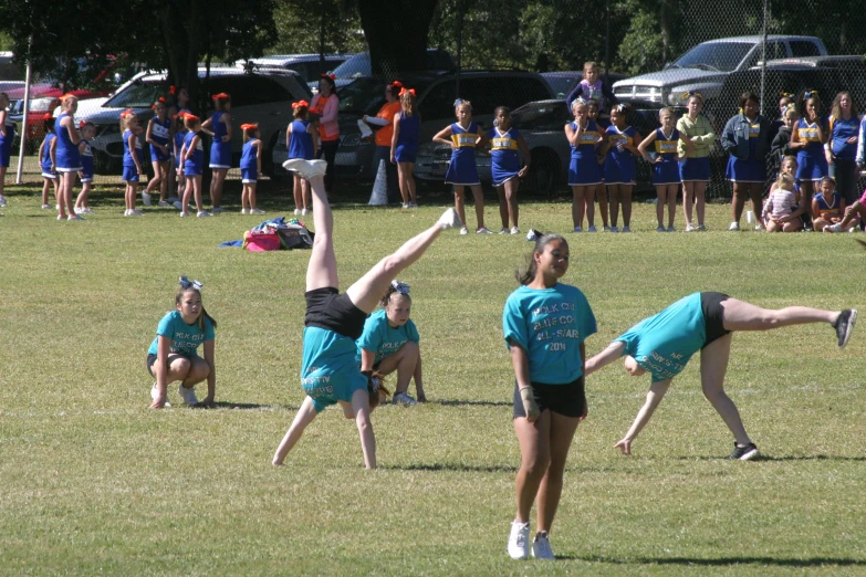 people in blue shirts and shorts with cheerleaders on a field