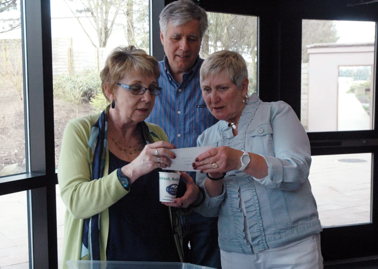 three older people in a room looking at soing