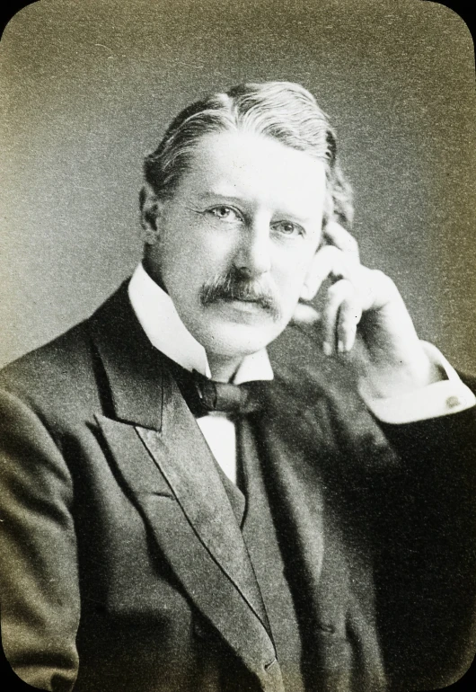 an old picture of a man in a suit and tie holding his fist up