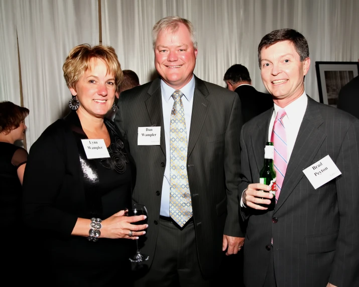 three business people standing in a room smiling at the camera