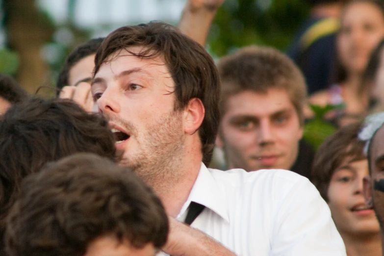 a man making a funny face as he stands in front of a group of people