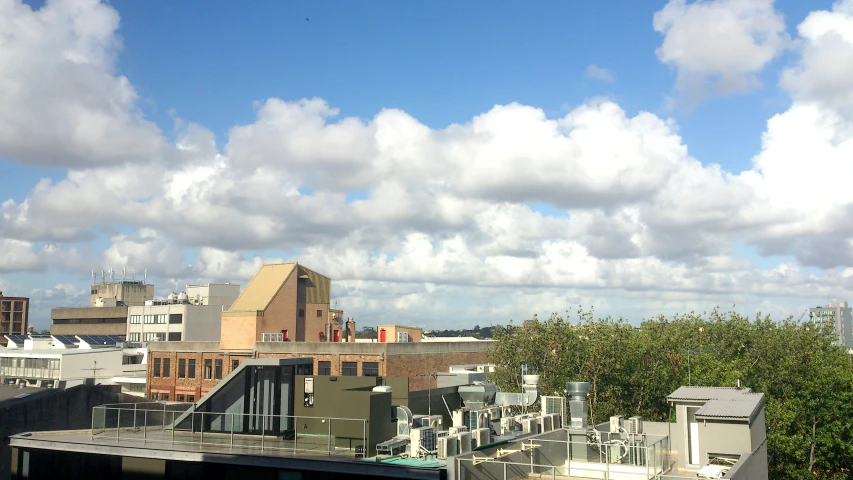 some buildings and green trees against a cloudy blue sky