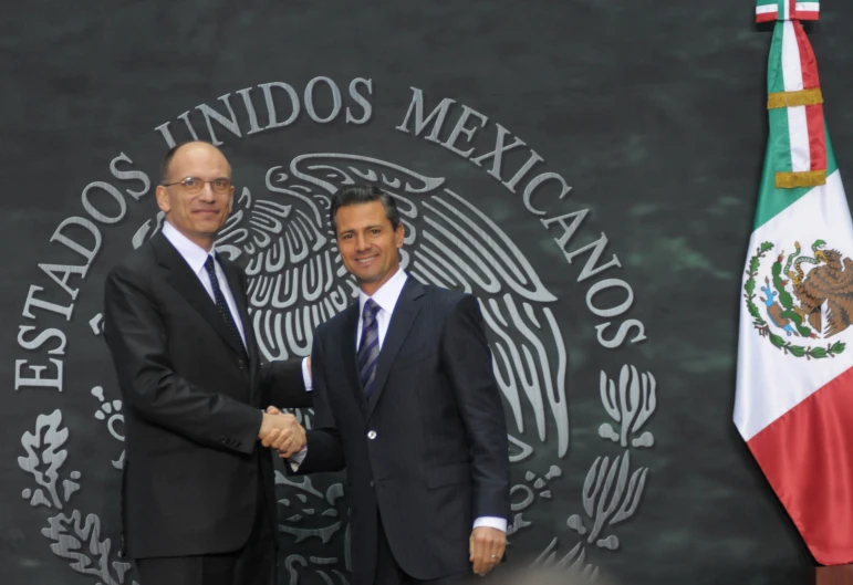 two men standing next to each other in front of flags