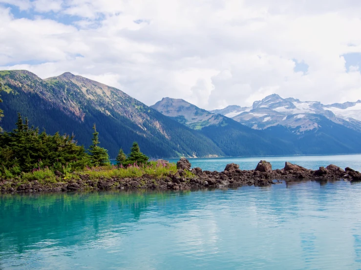 a lake is surrounded by rocky and forested mountains