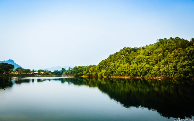 there are many green trees around the lake