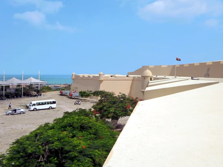 a long beige building has umbrellas and trees next to it