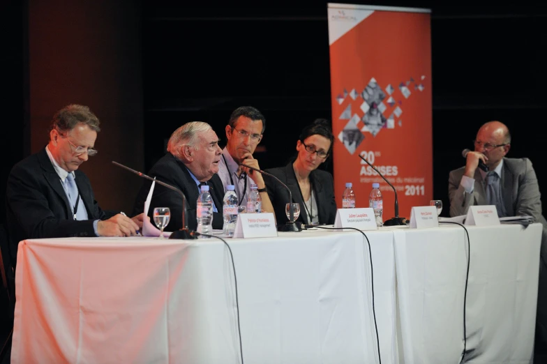 a few people sitting at a table and one person is holding a microphone