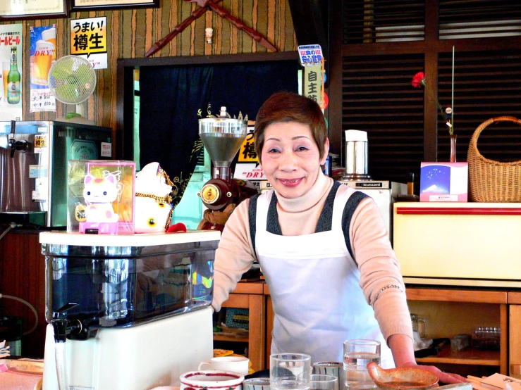 woman in an apron cooking donuts behind the counter